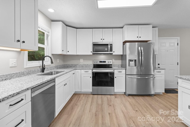219 Proctor Dr, Salisbury, NC 28147 - kitchen featuring appliances with stainless steel finishes, a sink, white cabinets, light wood-type flooring, and a textured ceiling