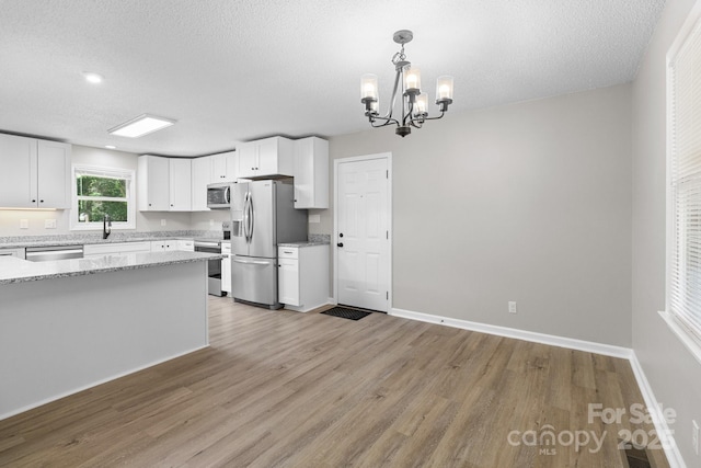 219 Proctor Dr, Salisbury, NC 28147 - kitchen featuring appliances with stainless steel finishes, light wood-style flooring, white cabinetry, a chandelier, and a textured ceiling