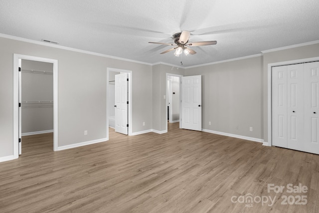 219 Proctor Dr, Salisbury, NC 28147 - unfurnished bedroom featuring light wood-type flooring, a textured ceiling, baseboards, a spacious closet, and crown molding