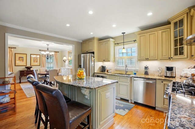 2025 Sagamore Rd, Charlotte, NC 28209 - kitchen featuring appliances with stainless steel finishes, cream cabinetry, a sink, light wood-style floors, and crown molding