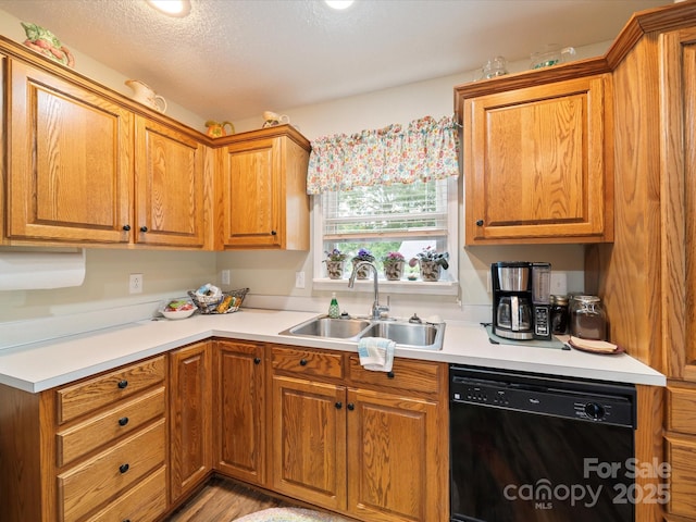 kitchen with black dishwasher, a sink, light countertops, and brown cabinetry