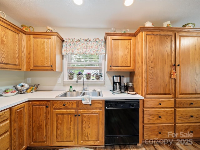 kitchen featuring black dishwasher, a sink, light countertops, and brown cabinetry