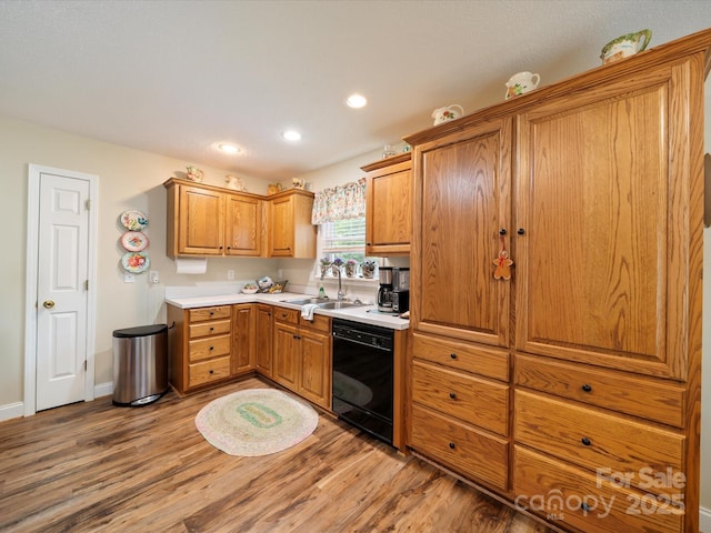 kitchen with black dishwasher, a sink, light wood-type flooring, brown cabinets, and recessed lighting