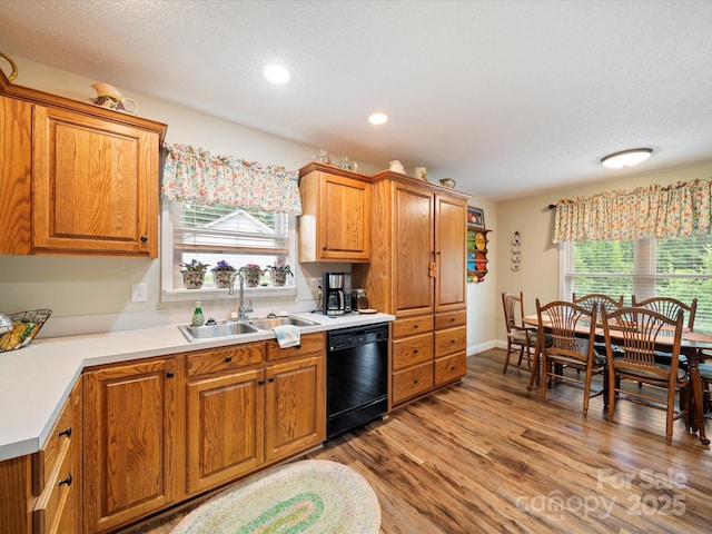 kitchen featuring dishwasher, a sink, plenty of natural light, light wood-type flooring, and recessed lighting
