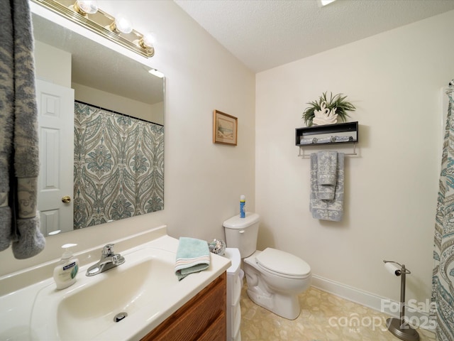 bathroom with toilet, vanity, baseboards, and a textured ceiling