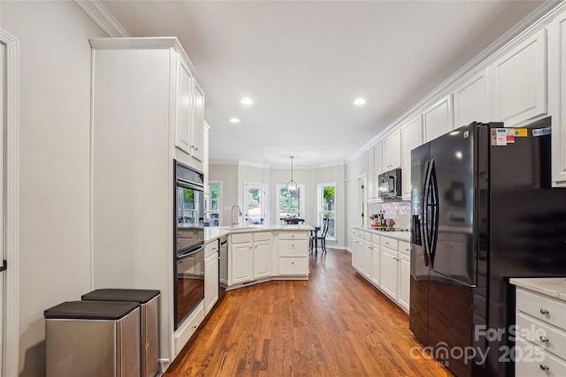 8612 Tintinhull Ln, Waxhaw, NC 28173 - kitchen with black appliances, a peninsula, crown molding, wood finished floors, and white cabinetry