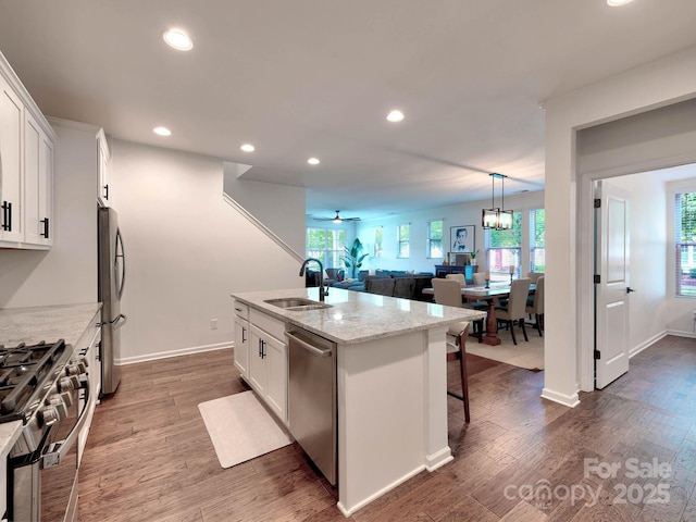 kitchen with stainless steel appliances, a sink, white cabinetry, dark wood finished floors, and recessed lighting