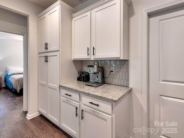 kitchen with dark wood-style floors, backsplash, white cabinetry, and light stone countertops