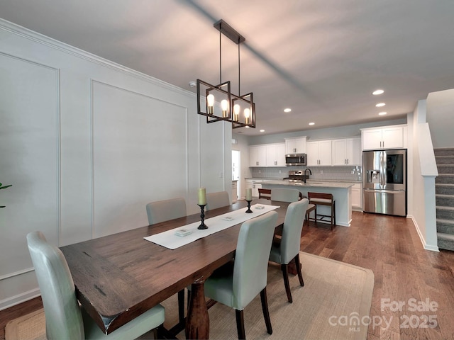 dining room featuring dark wood-style flooring, stairway, a chandelier, recessed lighting, and ornamental molding
