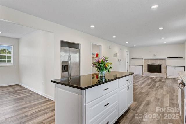 25 Southern Way, Nebo, NC 28761 - kitchen featuring stainless steel fridge with ice dispenser, light wood-style floors, white cabinets, recessed lighting, and a tile fireplace