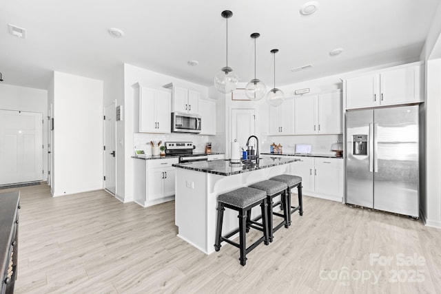 711 Bellmouth Rd, Clover, SC 29710 - kitchen featuring stainless steel appliances, a breakfast bar area, tasteful backsplash, light wood finished floors, and white cabinets