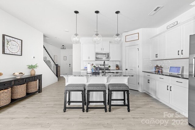711 Bellmouth Rd, Clover, SC 29710 - kitchen featuring appliances with stainless steel finishes, a kitchen bar, decorative backsplash, and white cabinetry