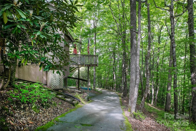 view of community featuring a deck, driveway, and a view of trees