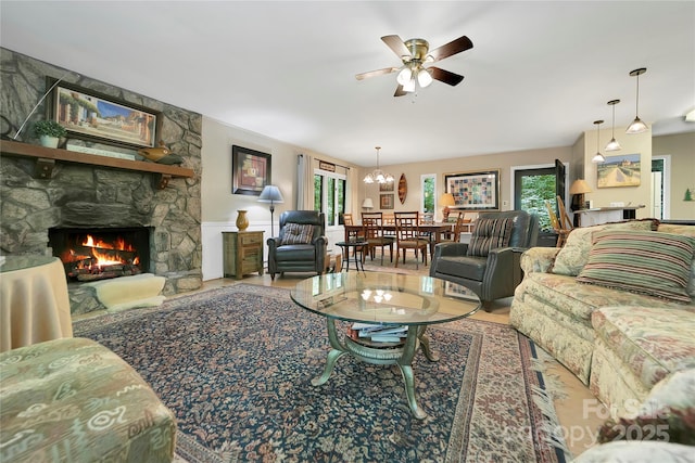living room with a fireplace, plenty of natural light, a ceiling fan, and a chandelier