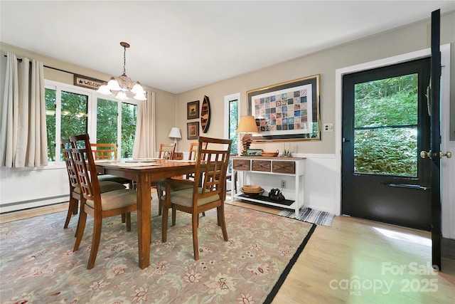 dining space featuring a chandelier, light wood-style flooring, and wainscoting