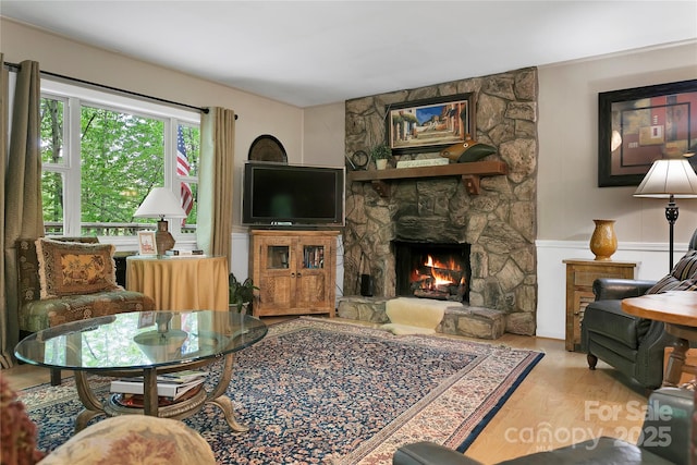 living area featuring a stone fireplace and wood finished floors