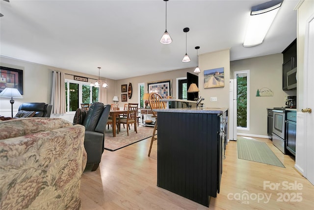 kitchen with stainless steel electric range, light wood-type flooring, a chandelier, light countertops, and decorative light fixtures