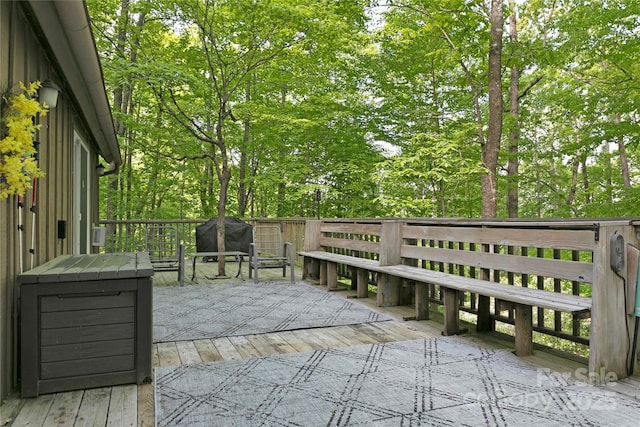 wooden deck with a grill and view of wooded area