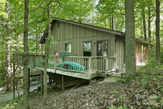 rear view of property with board and batten siding and a deck