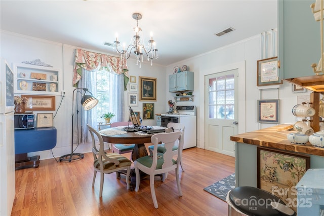 131 E Lexington Rd, Mocksville, NC 27028 - dining room featuring a chandelier, healthy amount of natural light, light wood-type flooring, ornamental molding, and washing machine and dryer