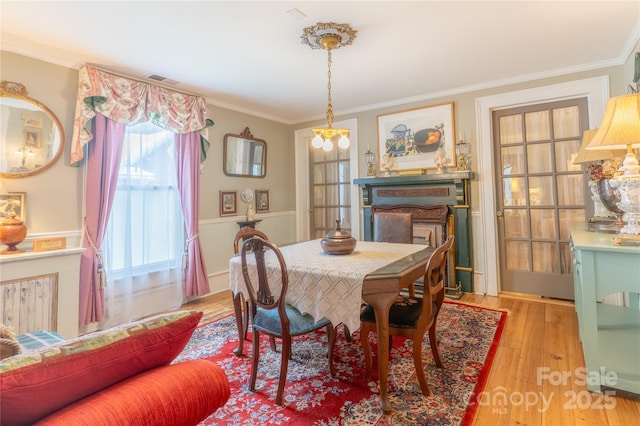 131 E Lexington Rd, Mocksville, NC 27028 - dining room with light wood-style flooring, ornamental molding, a fireplace, and a chandelier