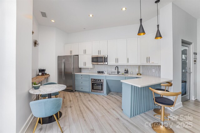 333 W Trade St Unit 1500, Charlotte, NC 28202 - kitchen featuring stainless steel appliances, a sink, light wood-style floors, light countertops, and white cabinetry