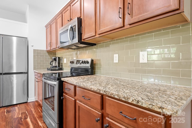 9437 Macquarie Ln, Charlotte, NC 28227 - kitchen with appliances with stainless steel finishes, decorative backsplash, light stone countertops, dark wood-type flooring, and brown cabinetry