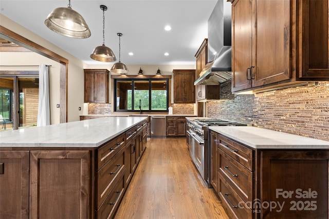 1822 Irby Rd, Monroe, NC 28112 - kitchen with appliances with stainless steel finishes, light wood finished floors, wall chimney exhaust hood, hanging light fixtures, and decorative backsplash