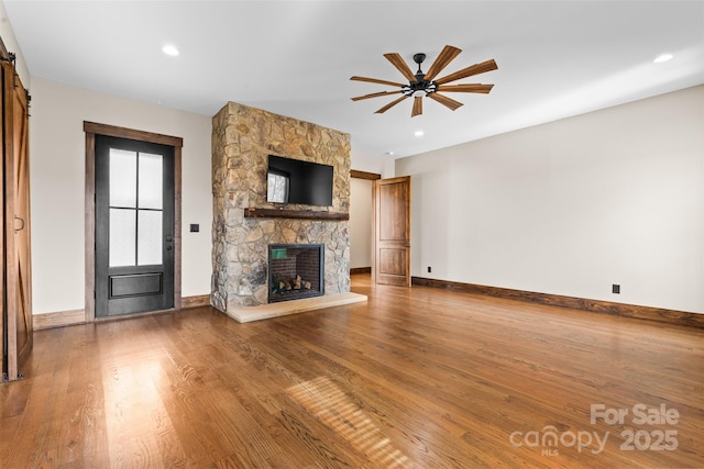 1822 Irby Rd, Monroe, NC 28112 - unfurnished living room featuring a stone fireplace, baseboards, a ceiling fan, wood finished floors, and recessed lighting