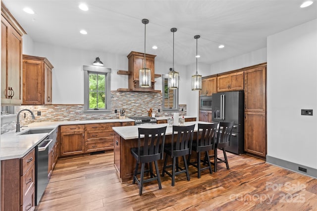 1822 Irby Rd, Monroe, NC 28112 - kitchen with appliances with stainless steel finishes, a center island, light countertops, brown cabinets, and light wood finished floors