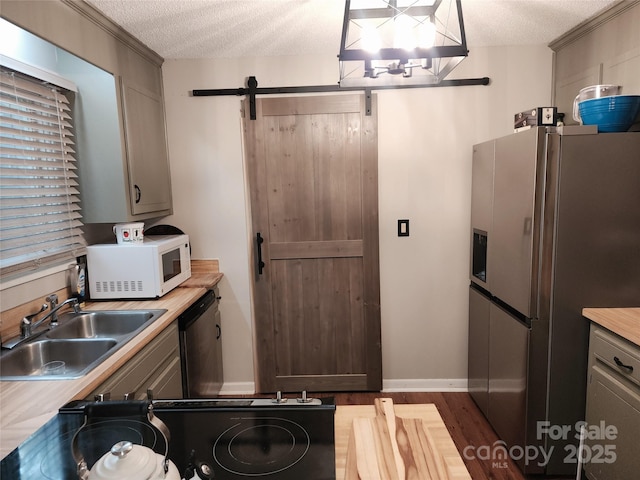 2800 Patio Ln, Gastonia, NC 28056 - kitchen with appliances with stainless steel finishes, a sink, a textured ceiling, a barn door, and light countertops