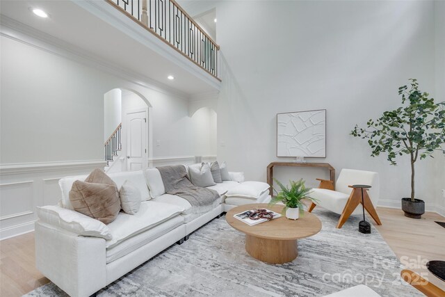 3741 Tea Olive Rd, Gastonia, NC 28056 - living room featuring a towering ceiling, arched walkways, wood finished floors, stairway, and a wainscoted wall