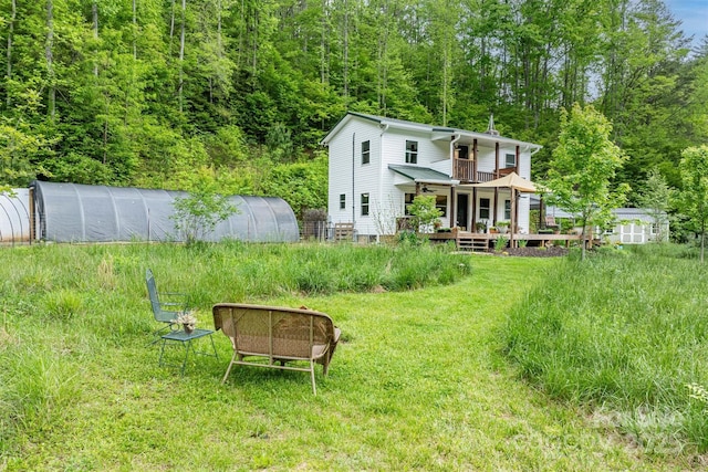 6470 Stone Mountain Rd, Lenoir, NC 28645 - view of grassy yard with a greenhouse, an outbuilding, a deck, and a view of trees