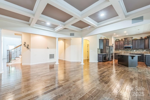 8336 Early Bird Way, Mint Hill, NC 28227 - kitchen with decorative columns, a breakfast bar, open floor plan, light wood-style flooring, and beamed ceiling