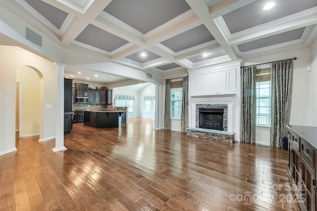 8336 Early Bird Way, Mint Hill, NC 28227 - unfurnished living room with dark wood-type flooring, baseboards, beam ceiling, ornate columns, and a stone fireplace