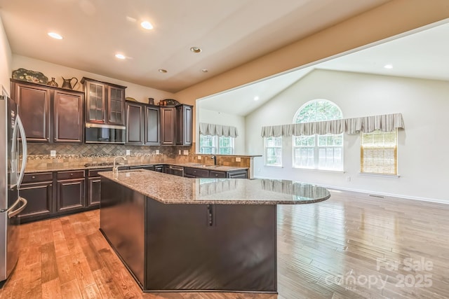 8336 Early Bird Way, Mint Hill, NC 28227 - kitchen with vaulted ceiling, a sink, freestanding refrigerator, light stone countertops, and an island with sink