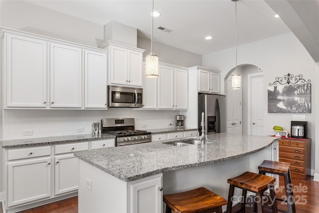 2021 Pinyon Ln, Lancaster, SC 29720 - kitchen featuring appliances with stainless steel finishes, a sink, arched walkways, white cabinets, and a kitchen bar