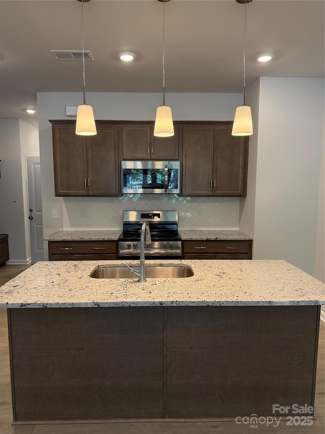 2910 Sloan Dr, Charlotte, NC 28208 - kitchen featuring appliances with stainless steel finishes, dark brown cabinets, tasteful backsplash, a sink, and recessed lighting