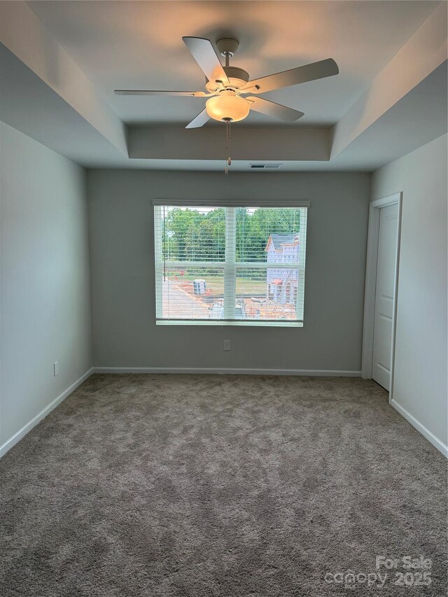 2910 Sloan Dr, Charlotte, NC 28208 - carpeted spare room featuring a raised ceiling, ceiling fan, and baseboards