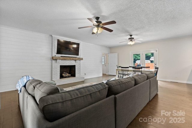 4916 Leepers Creek Rd, Maiden, NC 28650 - living area featuring a ceiling fan, wood finished floors, a fireplace, a textured ceiling, and baseboards