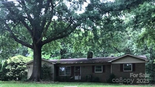 single story home featuring a chimney and a front lawn