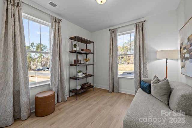 sitting room with light wood-type flooring, healthy amount of natural light, and baseboards