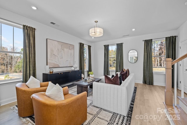 living area with baseboards, plenty of natural light, light wood-style floors, and recessed lighting