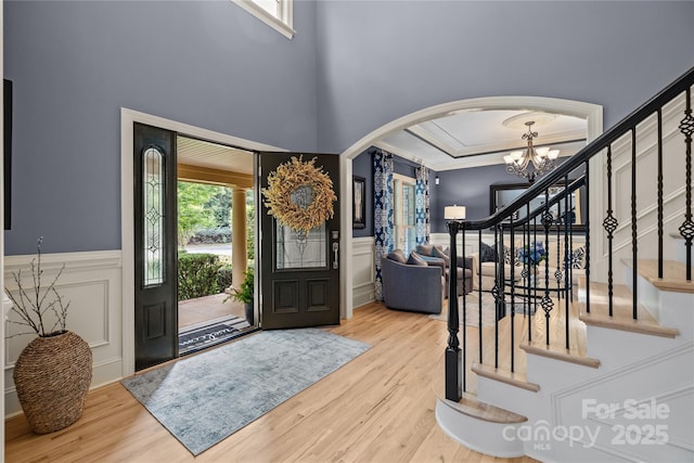 9021 Unbridle Ln, Waxhaw, NC 28173 - entrance foyer featuring arched walkways, a chandelier, wood finished floors, stairs, and ornamental molding