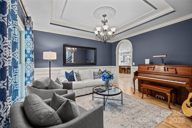 9021 Unbridle Ln, Waxhaw, NC 28173 - living area featuring a tray ceiling, arched walkways, a chandelier, wood finished floors, and a wainscoted wall