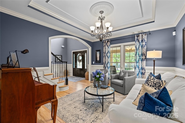 9021 Unbridle Ln, Waxhaw, NC 28173 - living room with a tray ceiling, arched walkways, a chandelier, crown molding, and wood finished floors