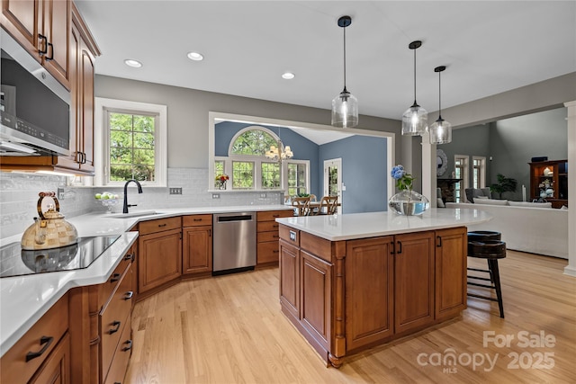 9021 Unbridle Ln, Waxhaw, NC 28173 - kitchen featuring appliances with stainless steel finishes, a sink, light wood-style floors, a breakfast bar, and recessed lighting
