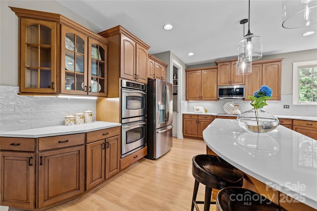9021 Unbridle Ln, Waxhaw, NC 28173 - kitchen with appliances with stainless steel finishes, a breakfast bar, light countertops, glass insert cabinets, and recessed lighting