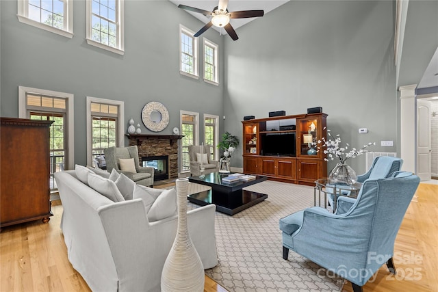 9021 Unbridle Ln, Waxhaw, NC 28173 - living area with a towering ceiling, a ceiling fan, a stone fireplace, wood finished floors, and ornate columns