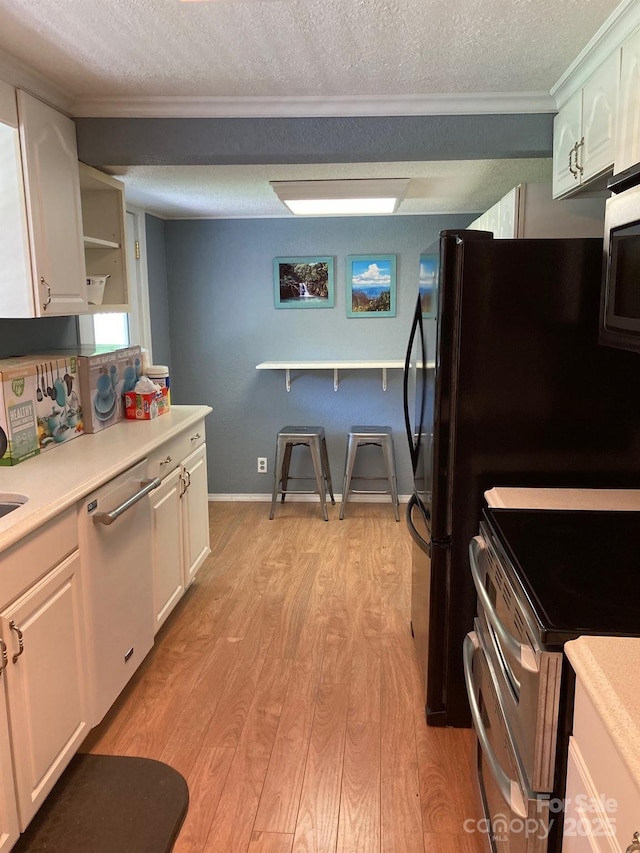 kitchen featuring appliances with stainless steel finishes, crown molding, a textured ceiling, white cabinetry, and light wood-style floors